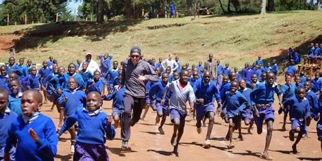 School children running with a visitor